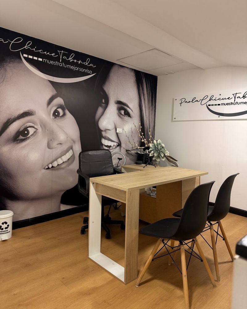 Consultation desk with black chairs in front of the clinic's photo mural