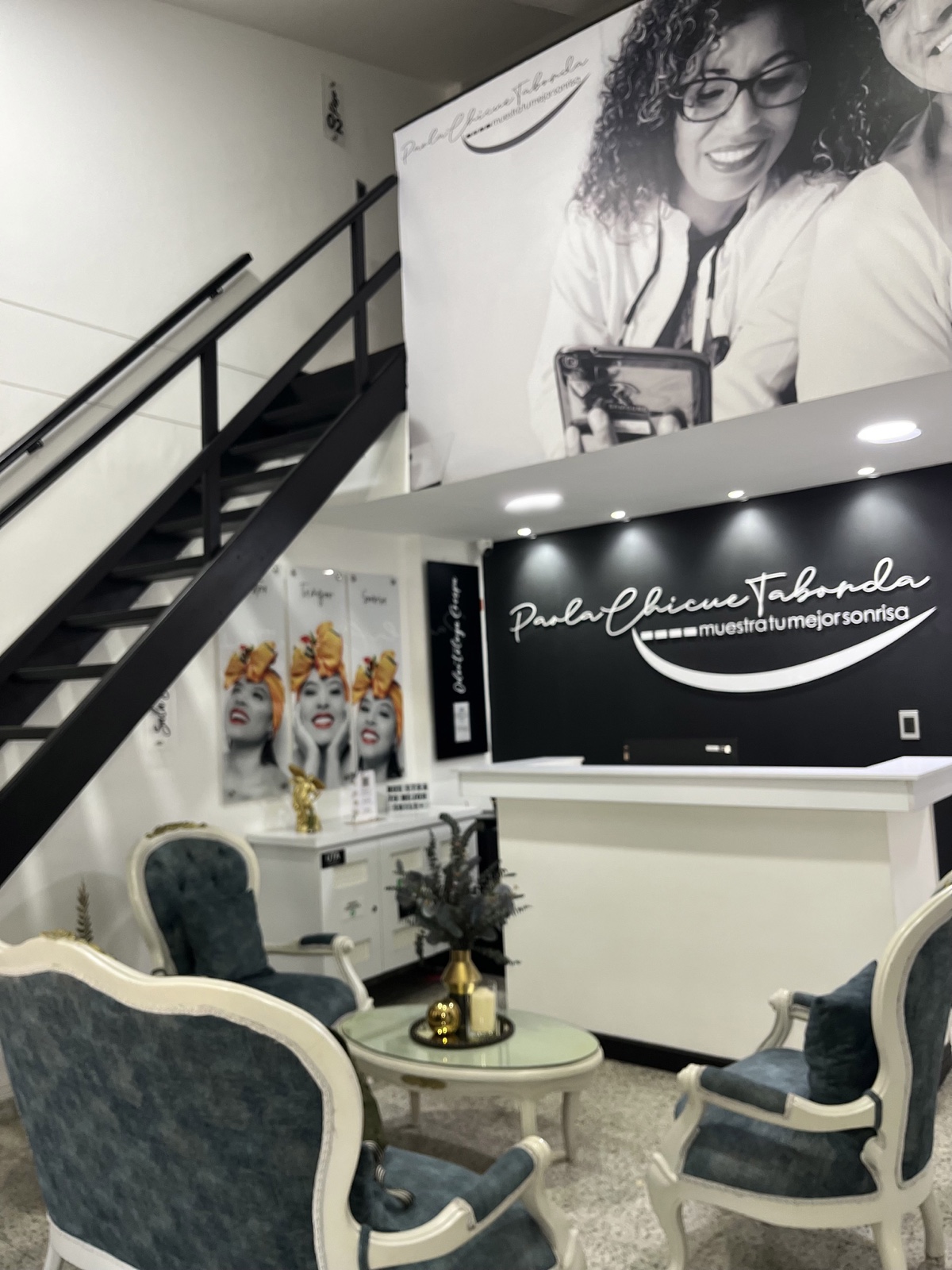Reception desk with 'Paola Chicue Taborda — muestra tu mejor sonrisa' branding